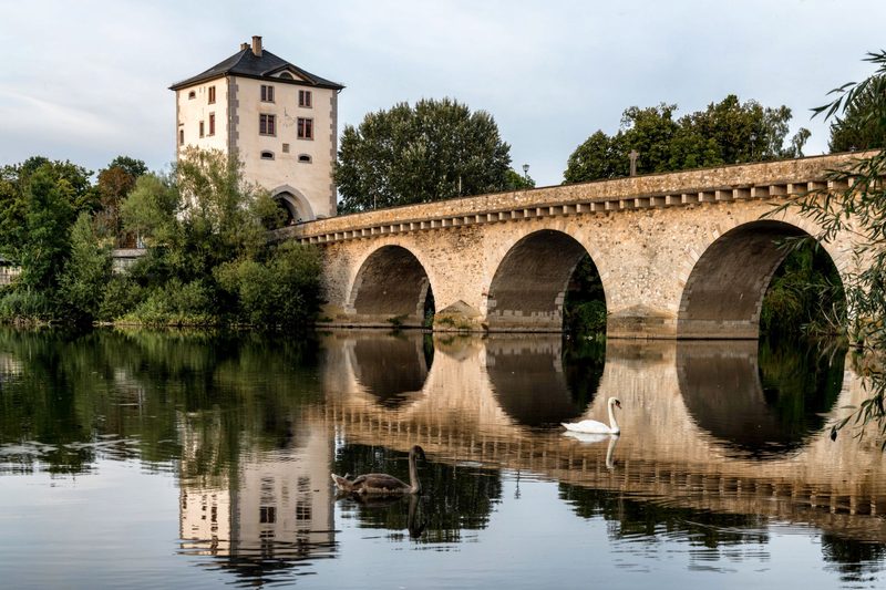 Die alte Steinbrücke über den Fluss, im Wasser spiegeln sich ihre Bögen