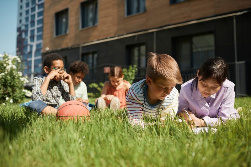 Kinder lernen und spielen auf der Wiese vor einem Gebäude
