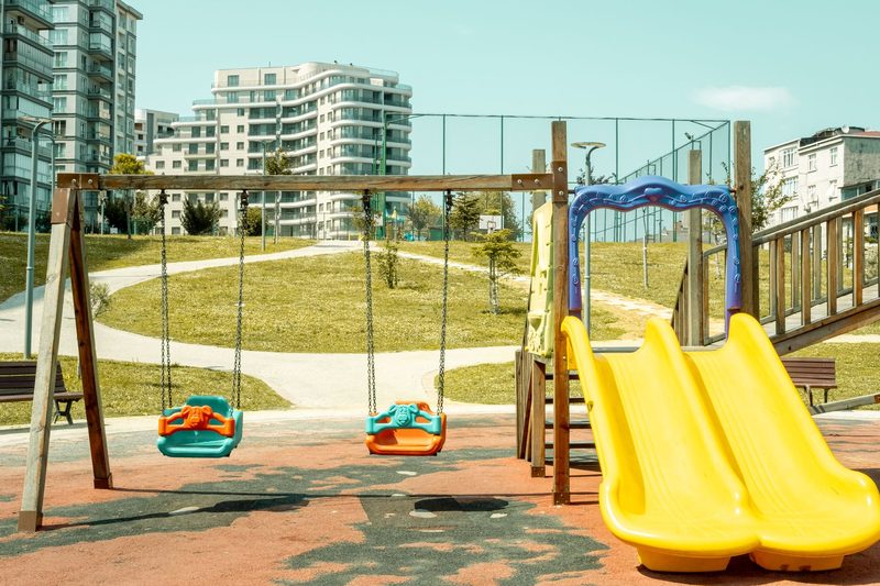 Spielplatz mit Schaukeln und gelber Rutsche