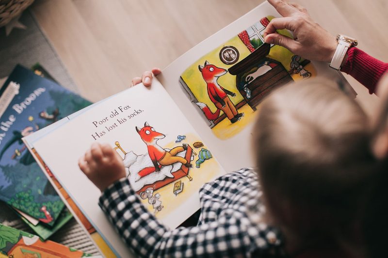Ein Kind und ein Erwachsener blättern in einem Bilderbuch