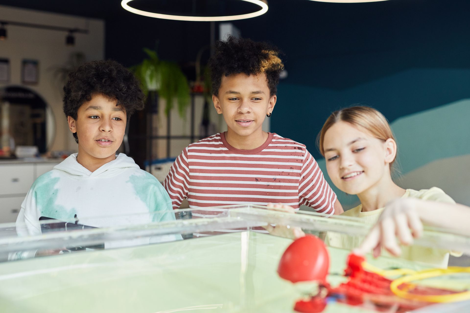 Drei Kinder bauen mit einem Roboter-Set an einem Wasserbecken