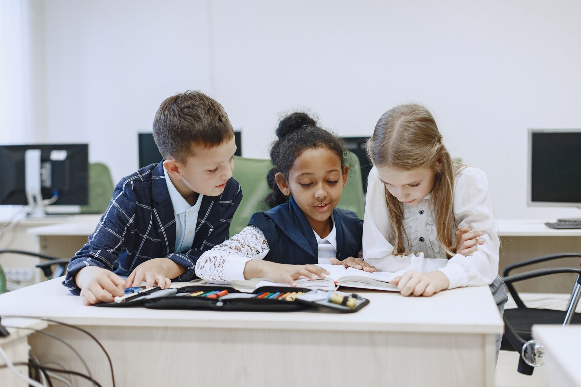 Drei Kinder arbeiten an einem Tisch zusammen an einem Buch